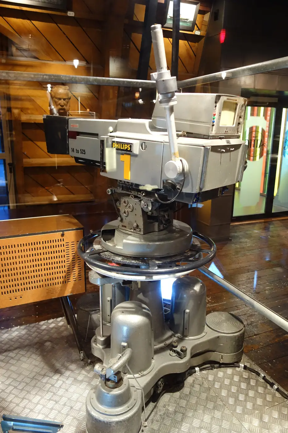A large grey television studio camera on a heavy wheeled pedestal, displayed in a museum