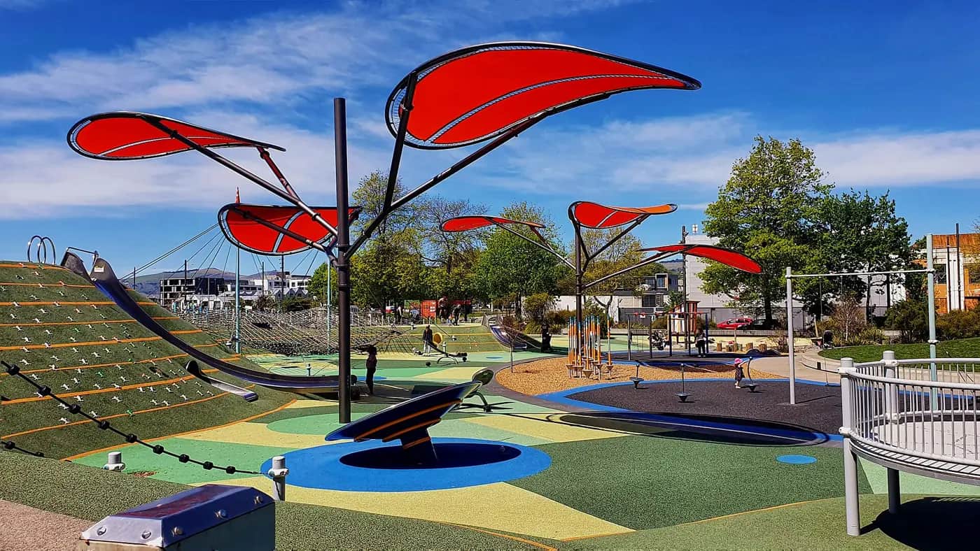 The Margaret Mahy Playground in Christchurch with red leaf-shaped shade sails, a giant slide and colourful play surfaces