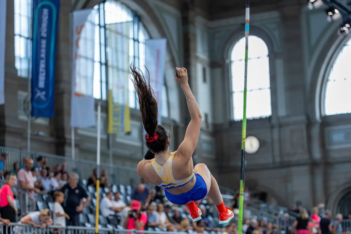 New Zealand pole vaulter Eliza McCartney arching over the bar during a competition, seen from behind