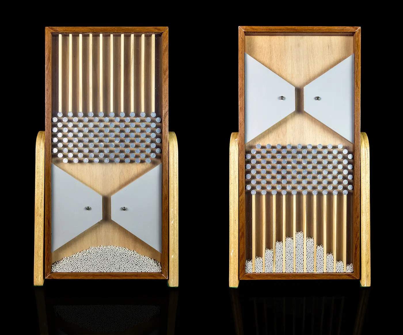 Two wooden Galton boards: in one the beads sit in a heap at the bottom, in the other they have fallen through rows of pins into columns forming a hill shape