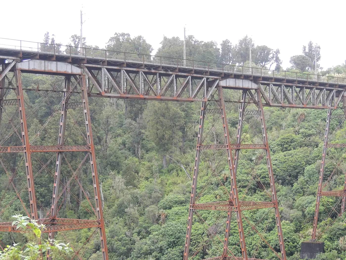 The tall steel legs of the Makatote railway viaduct rise above native bush, criss-crossed with diagonal bracing.